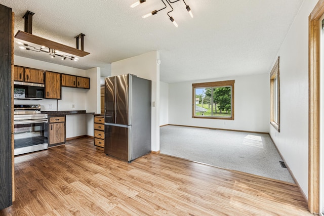 2140 Prospect Dr NE, Saint Cloud, MN 56304 - kitchen featuring appliances with stainless steel finishes, dark countertops, light wood finished floors, open floor plan, and a textured ceiling