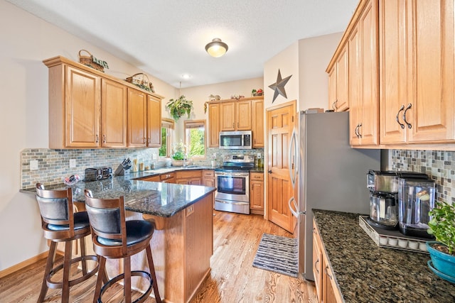 1893 White Oak Dr, Chaska, MN 55318 - kitchen featuring appliances with stainless steel finishes, a peninsula, light wood finished floors, and a breakfast bar