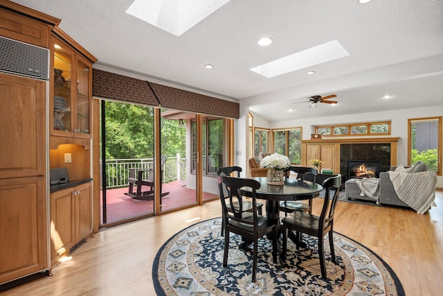 6136 Arctic Way, Edina, MN 55436 - dining room with a skylight, light wood-style flooring, a tiled fireplace, recessed lighting, and a textured ceiling