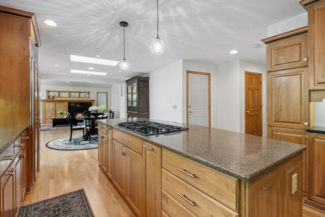 6136 Arctic Way, Edina, MN 55436 - kitchen with gas cooktop, light wood-style flooring, a kitchen island, dark stone countertops, and pendant lighting