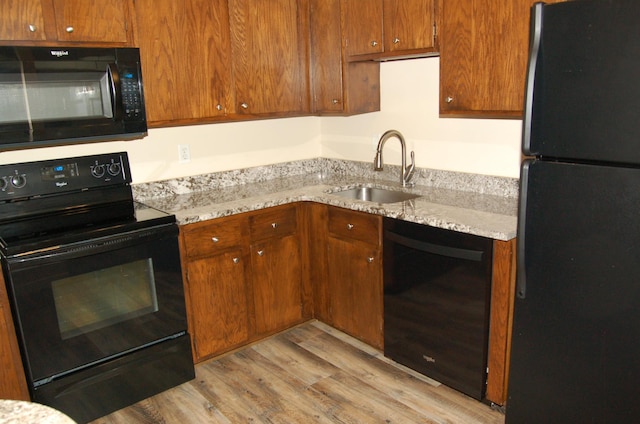 1903 Silver Bell Rd Unit 219, Eagan, MN 55122 - kitchen with black appliances, a sink, light wood finished floors, light stone counters, and brown cabinets