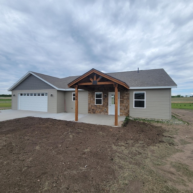 164 Cozy Oak Dr E, Ottertail, MN 56571 - ranch-style house with an attached garage, concrete driveway, stone siding, a patio area, and a shingled roof