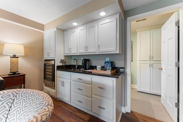 6813 Boudin St NE, Prior Lake, MN 55372 - bedroom featuring wine cooler, a textured ceiling, recessed lighting, and dark wood-style flooring