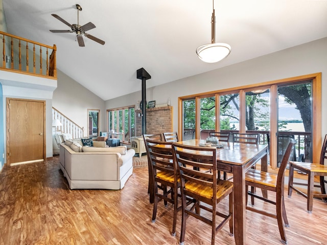 21534 275th Ave, Glenwood Twp, MN 56381 - dining space with a ceiling fan, stairway, light wood finished floors, a wood stove, and high vaulted ceiling
