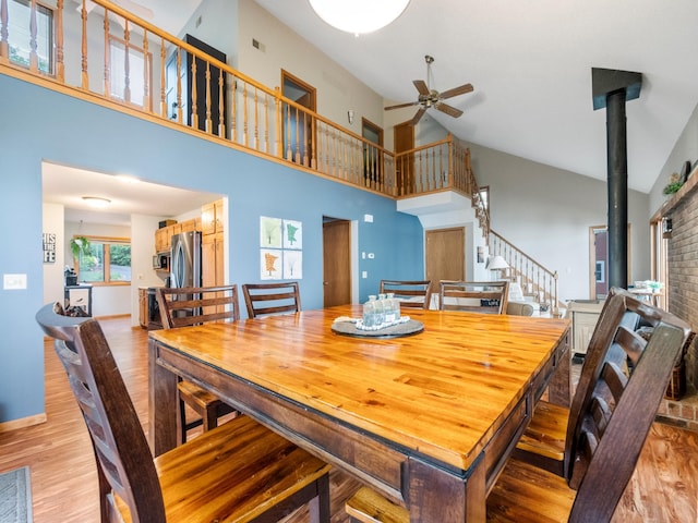 21534 275th Ave, Glenwood Twp, MN 56381 - dining space featuring a ceiling fan, light wood-type flooring, high vaulted ceiling, a wood stove, and stairway