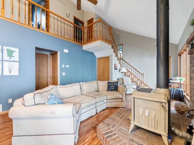 21534 275th Ave, Glenwood Twp, MN 56381 - living area featuring wood finished floors, a wood stove, high vaulted ceiling, ceiling fan, and stairway