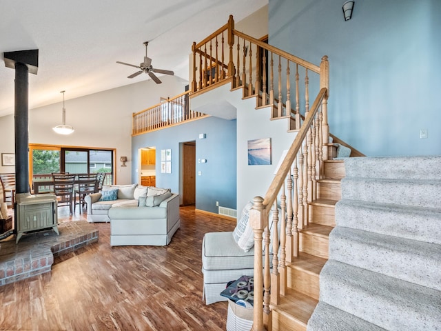 21534 275th Ave, Glenwood Twp, MN 56381 - living room featuring a wood stove, stairway, a ceiling fan, high vaulted ceiling, and wood finished floors