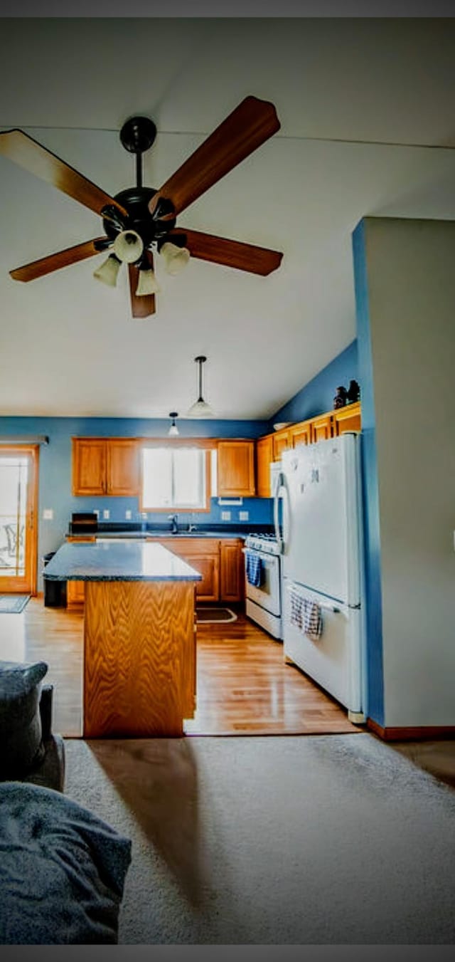 2030 Joes Lake Rd SE, Cambridge, MN 55008 - kitchen featuring white appliances, lofted ceiling, brown cabinetry, ceiling fan, and light wood-style flooring