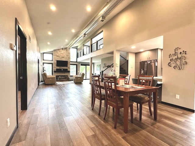 1953 Cecilee St, Worthington, MN 56187 - dining area with wood-type flooring, a fireplace, stairs, and high vaulted ceiling
