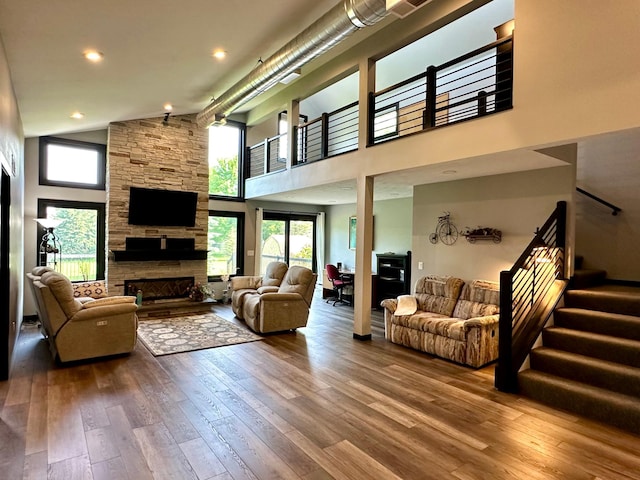 1953 Cecilee St, Worthington, MN 56187 - living area with a towering ceiling, wood-type flooring, stairway, a stone fireplace, and recessed lighting