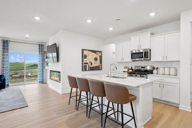 2451 Jandell Ave NE, Saint Michael, MN 55376 - kitchen with appliances with stainless steel finishes, light wood-type flooring, backsplash, an island with sink, and light countertops