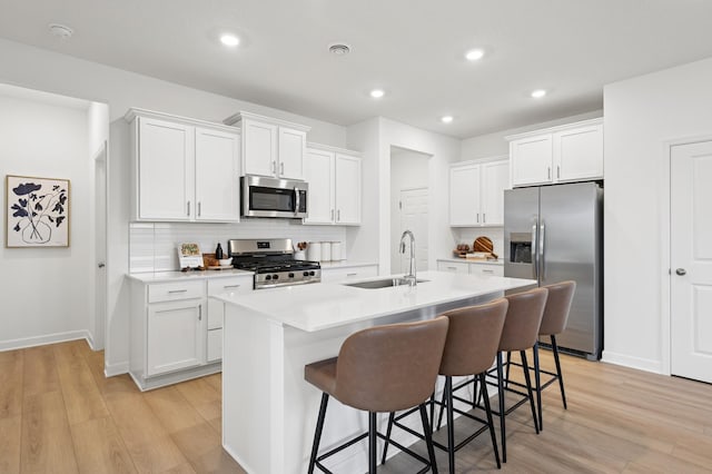 2451 Jandell Ave NE, Saint Michael, MN 55376 - kitchen featuring stainless steel appliances, light wood-style flooring, a center island with sink, backsplash, and recessed lighting