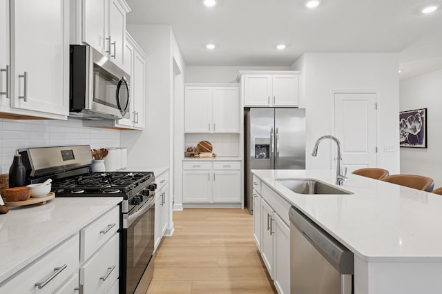 2451 Jandell Ave NE, Saint Michael, MN 55376 - kitchen featuring appliances with stainless steel finishes, light wood-type flooring, a kitchen island with sink, white cabinets, and recessed lighting