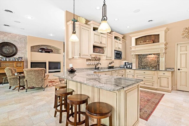 79394 Long Lake Rd, Kettle River Twp, MN 55795 - kitchen with cream cabinetry, stainless steel microwave, light stone countertops, a breakfast bar, and recessed lighting