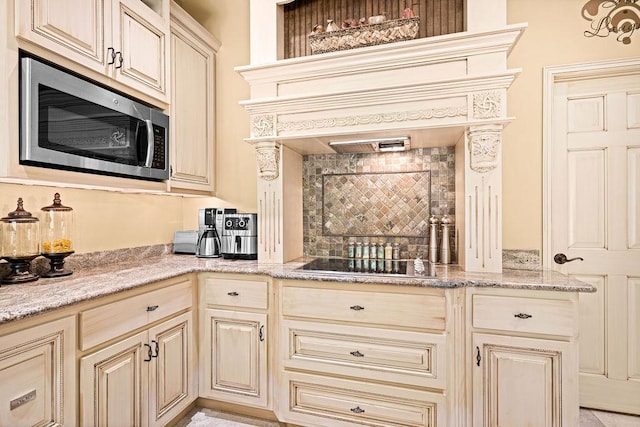 79394 Long Lake Rd, Kettle River Twp, MN 55795 - kitchen featuring stainless steel microwave, cream cabinetry, black electric stovetop, and backsplash