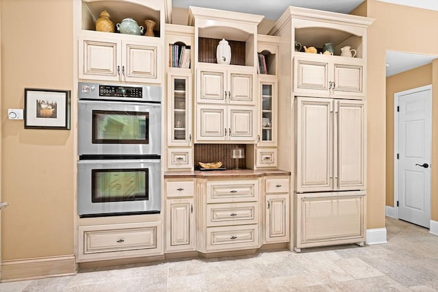 79394 Long Lake Rd, Kettle River Twp, MN 55795 - kitchen featuring open shelves, stainless steel double oven, baseboards, and cream cabinetry