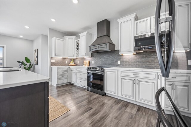7886 Firefly Ln, Horace, ND 58047 - kitchen featuring custom exhaust hood, stainless steel appliances, tasteful backsplash, light countertops, and dark wood-type flooring