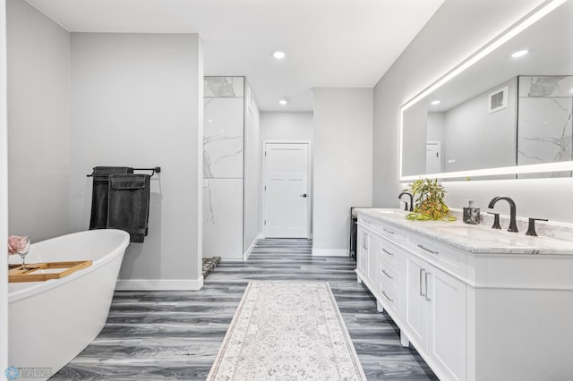 7886 Firefly Ln, Horace, ND 58047 - full bathroom with baseboards, double vanity, a freestanding tub, wood finished floors, and recessed lighting