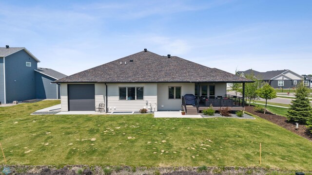 7886 Firefly Ln, Horace, ND 58047 - rear view of house with a lawn, an attached garage, a wooden deck, and a shingled roof