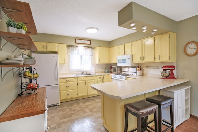 308 18th Ave NE, Waseca, MN 56093 - kitchen with white appliances, a peninsula, a sink, a kitchen bar, and light countertops