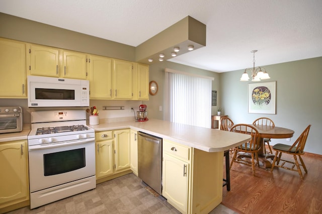 308 18th Ave NE, Waseca, MN 56093 - kitchen with white appliances, a peninsula, light countertops, a chandelier, and a textured ceiling