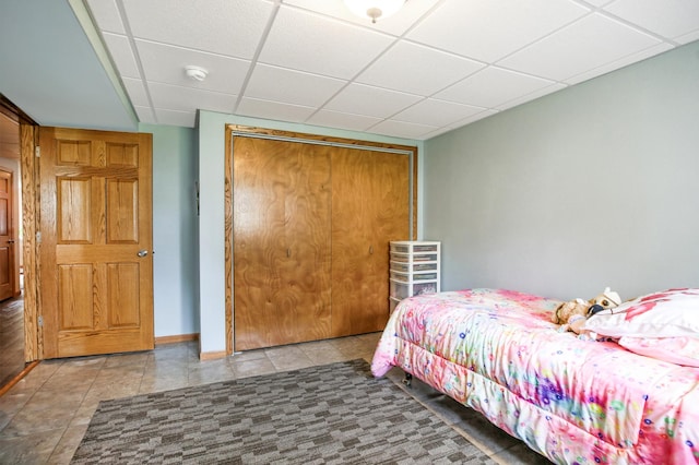 308 18th Ave NE, Waseca, MN 56093 - tiled bedroom featuring a closet, a paneled ceiling, and baseboards