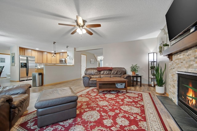 10542 188th Ave NW, Elk River, MN 55330 - living room with a ceiling fan, a stone fireplace, light wood-type flooring, a textured ceiling, and baseboards