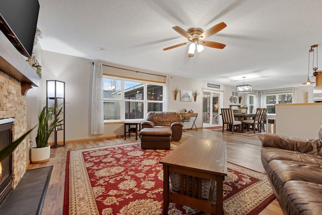 10542 188th Ave NW, Elk River, MN 55330 - living room with a stone fireplace, a ceiling fan, healthy amount of natural light, a textured ceiling, and wood finished floors