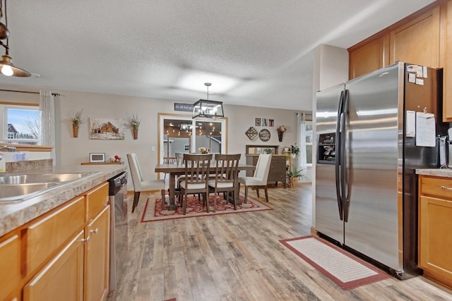 10542 188th Ave NW, Elk River, MN 55330 - kitchen with stainless steel fridge, light wood-style flooring, a sink, light countertops, and a textured ceiling
