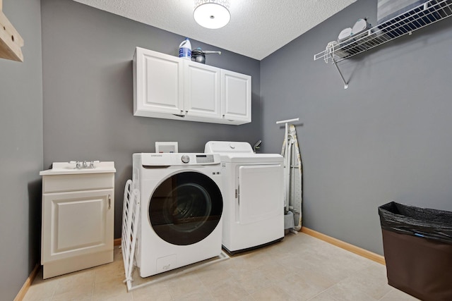 10542 188th Ave NW, Elk River, MN 55330 - laundry area featuring washing machine and clothes dryer, cabinet space, baseboards, a textured ceiling, and light tile patterned flooring