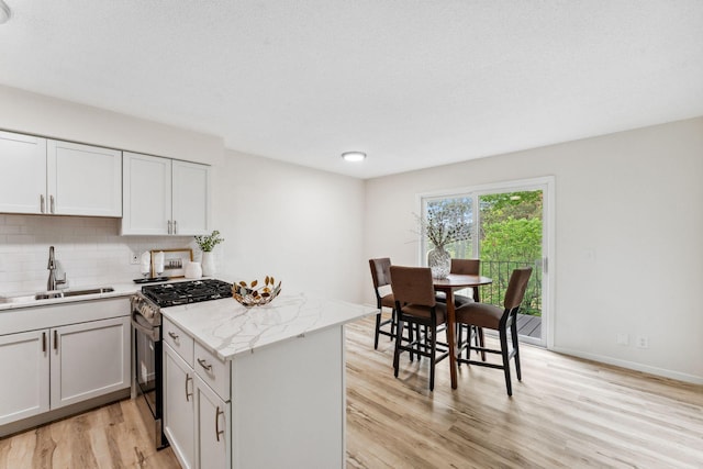 5707 80th Ave N, Brooklyn Park, MN 55443 - kitchen with stainless steel range with gas stovetop, a sink, light wood-style floors, backsplash, and light stone countertops
