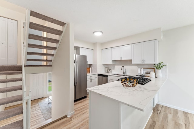 5707 80th Ave N, Brooklyn Park, MN 55443 - kitchen featuring appliances with stainless steel finishes, a peninsula, light wood-style floors, and a sink