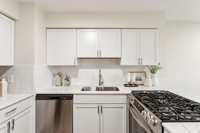 5707 80th Ave N, Brooklyn Park, MN 55443 - kitchen featuring appliances with stainless steel finishes, a sink, white cabinets, decorative backsplash, and light stone countertops