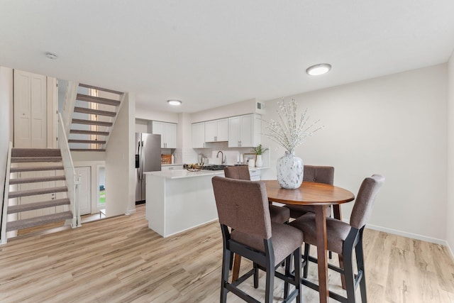 5707 80th Ave N, Brooklyn Park, MN 55443 - dining area featuring light wood-style flooring, stairs, and baseboards
