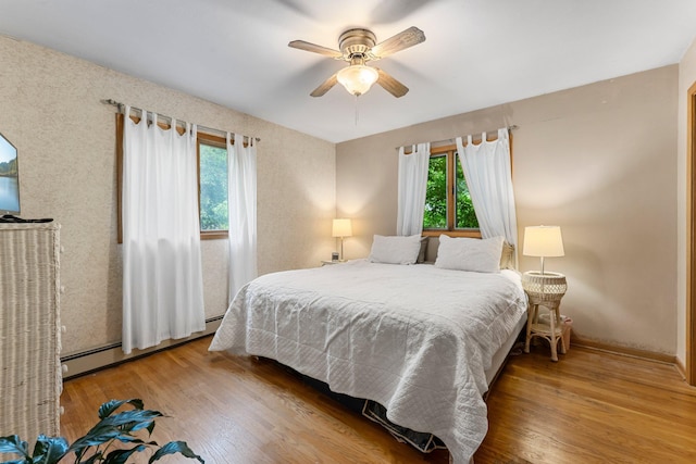 10785 56th St, Palmer Twp, MN 55319 - bedroom with wood finished floors, a ceiling fan, and a baseboard heating unit