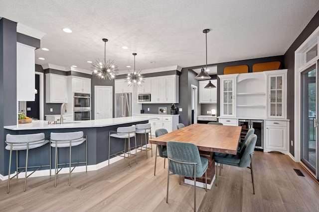 330 Lythrum Ln, Medina, MN 55340 - dining area featuring light wood finished floors, a chandelier, recessed lighting, ornamental molding, and wine cooler