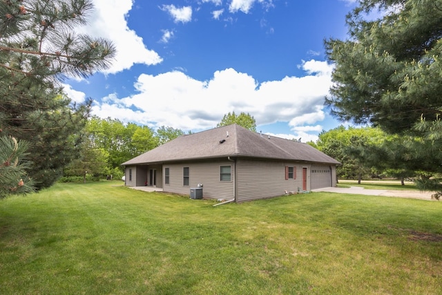 67457 152nd Ave, Greenfield Twp, MN 55981 - view of side of home featuring concrete driveway, central AC unit, a yard, a garage, and a shingled roof
