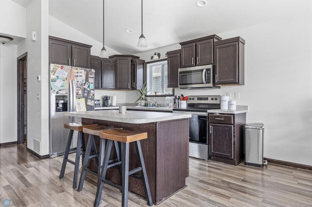 2128 Admiral Dr W, West Fargo, ND 58078 - kitchen featuring stainless steel appliances, dark brown cabinets, vaulted ceiling, a kitchen island, and light countertops