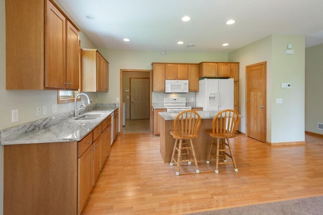 1223 Cypress Dr W, Annandale, MN 55302 - kitchen with white appliances, a sink, a kitchen island, light wood-style flooring, and a breakfast bar area