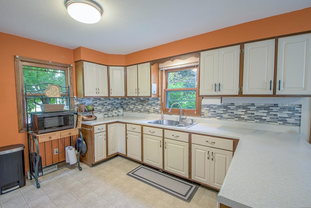 1221 11th St SE, Saint Cloud, MN 56304 - kitchen featuring a sink, stainless steel microwave, light countertops, and decorative backsplash
