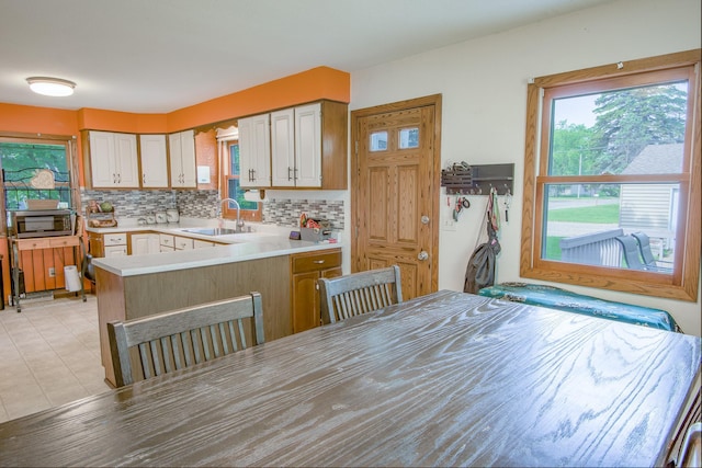 1221 11th St SE, Saint Cloud, MN 56304 - kitchen featuring a sink, decorative backsplash, light countertops, a peninsula, and light tile patterned floors