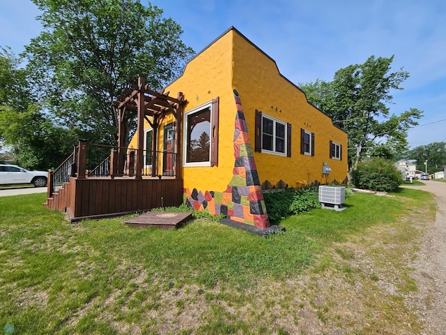 609 1st St N, Wahpeton, ND 58075 - view of property exterior with a lawn, stucco siding, a pergola, central air condition unit, and a wooden deck