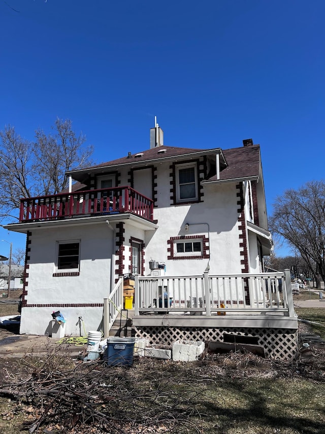 722 2nd St SW, Willmar, MN 56201 - rear view of property featuring a balcony, a chimney, stucco siding, and a wooden deck