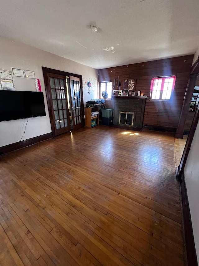 722 2nd St SW, Willmar, MN 56201 - unfurnished living room with hardwood / wood-style flooring, wooden walls, a fireplace, baseboards, and french doors