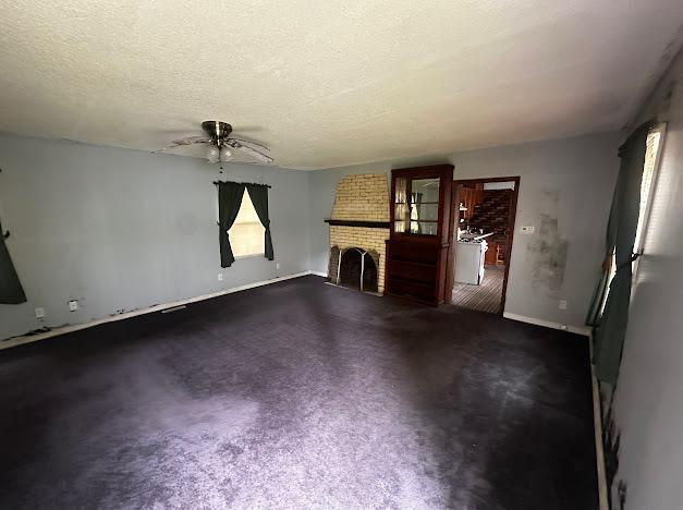 5336 44th Ave S, Minneapolis, MN 55417 - unfurnished living room featuring ceiling fan, a fireplace, baseboards, and a textured ceiling