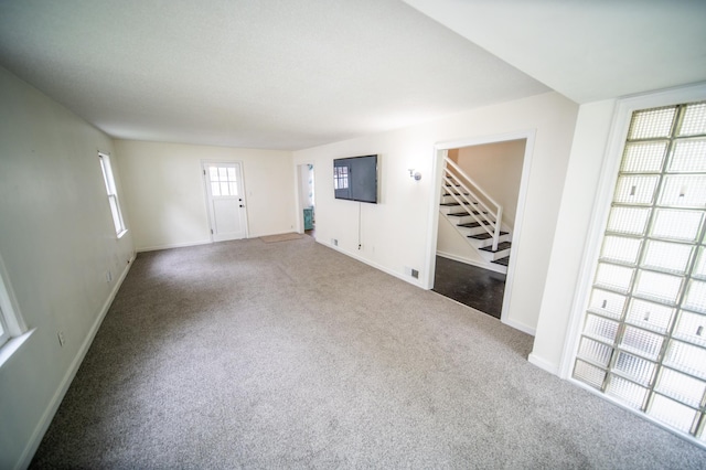 109 2nd St SW, Blooming Prairie, MN 55917 - unfurnished living room featuring stairway, baseboards, and carpet flooring