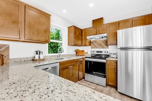 729 Burr St N, Saint Paul, MN 55130 - kitchen with stainless steel appliances, under cabinet range hood, a sink, light stone countertops, and brown cabinetry