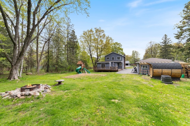 331 Locust St, Duluth, MN 55811 - view of green lawn with a fire pit, a playground, a deck, and an outbuilding