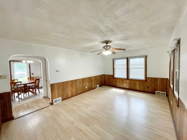 111 Park Ave, Springfield, MN 56087 - spare room featuring arched walkways, light wood-style flooring, wainscoting, wood walls, and a textured ceiling
