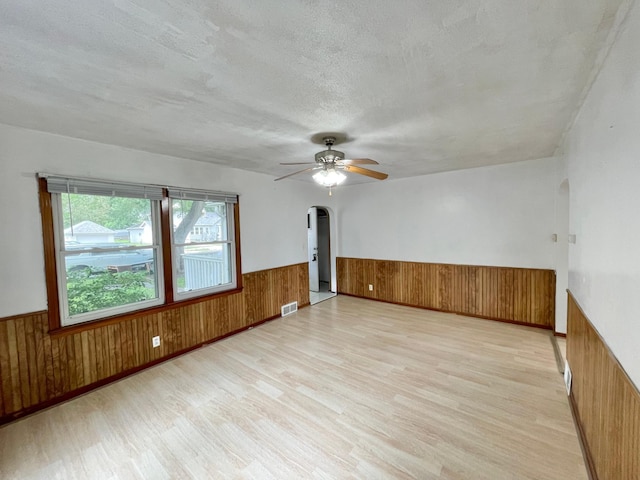 111 Park Ave, Springfield, MN 56087 - spare room with arched walkways, wainscoting, wood walls, light wood finished floors, and a ceiling fan